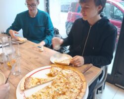 dwóch uczniów jedzących pizzę z restauracji