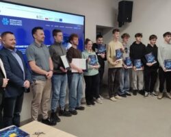grupa uczniów z dyplomami przed niebieskim ekranem