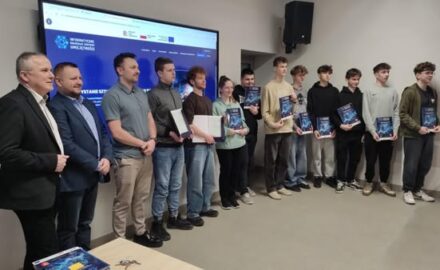 grupa uczniów z dyplomami przed niebieskim ekranem