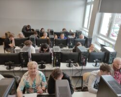Seniorzy z uczniami pracują przy komputerach