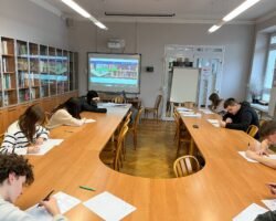 uczniowie siedzący prze stole konferencyjnym