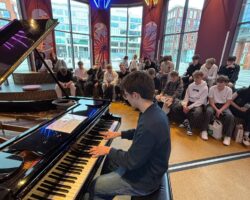 uczniowie słuchający gry na pianinie