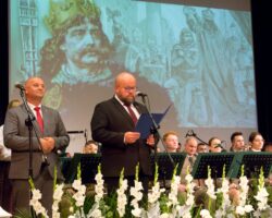 Prowadzący stoi przed mikrofonem