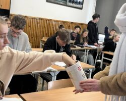 uczniowie dają "grosze" do skarbonki